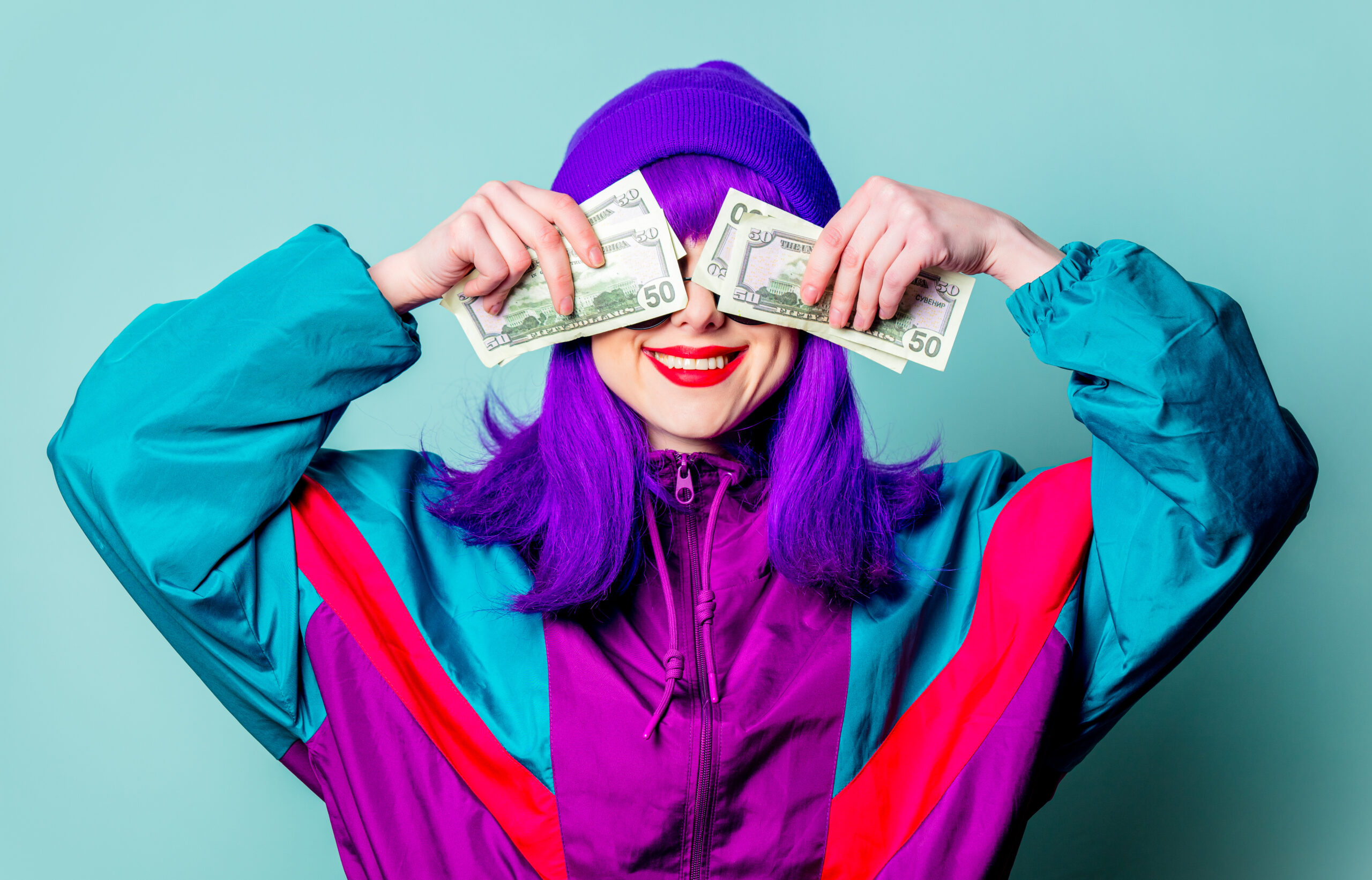 Smiling white girl with purple hair and 80s tracksuit hold cash